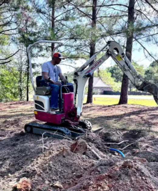 Dr. Samuel Jones operating a small excavator to reroute his water line