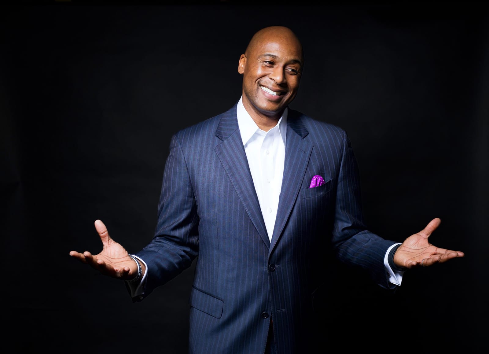 Dr. Samuel Jones gesturing warmly in a navy suit